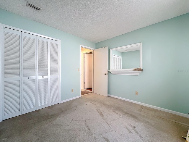 unfurnished bedroom featuring light carpet, a closet, and a textured ceiling