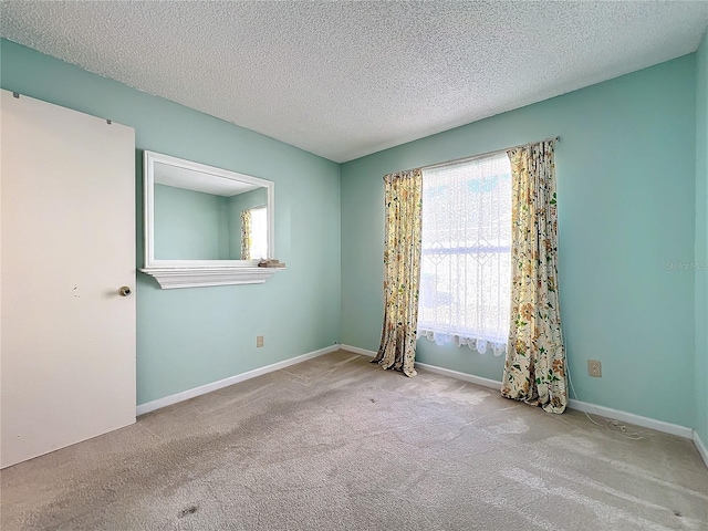 carpeted empty room with a textured ceiling