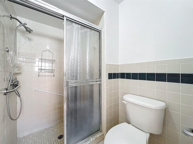 bathroom with toilet, a shower with door, and tile walls