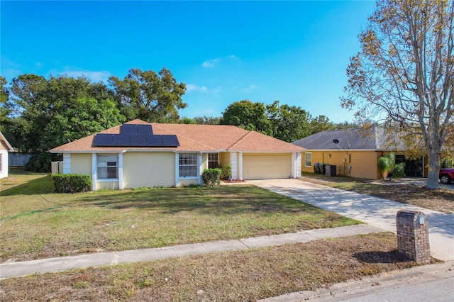 single story home featuring solar panels, a garage, a front lawn, and central air condition unit