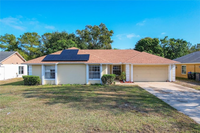 ranch-style home with a garage, a front yard, and solar panels