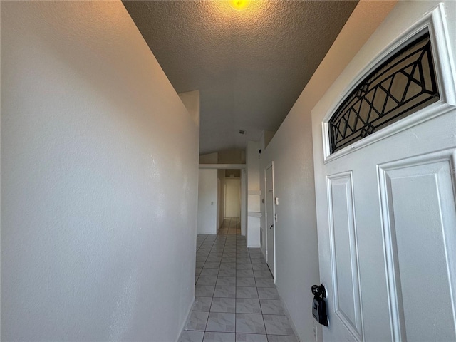 corridor with light tile patterned floors and a textured ceiling