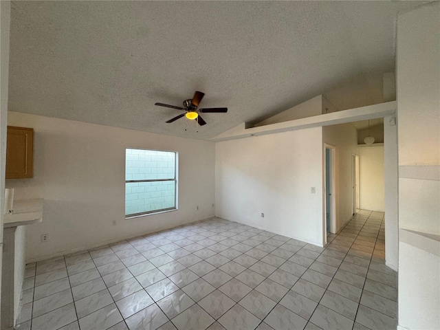 empty room with a textured ceiling, ceiling fan, lofted ceiling, and light tile patterned flooring