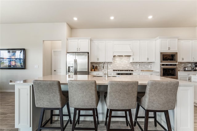 kitchen featuring a large island, sink, white cabinetry, stainless steel appliances, and custom exhaust hood