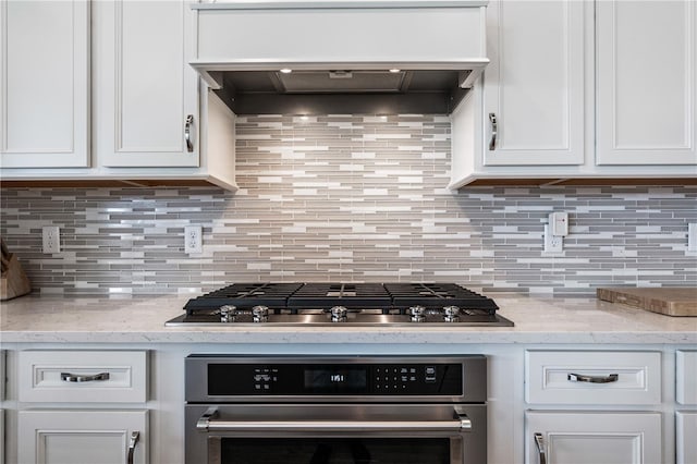 kitchen featuring white cabinetry, stainless steel appliances, custom range hood, and light stone counters