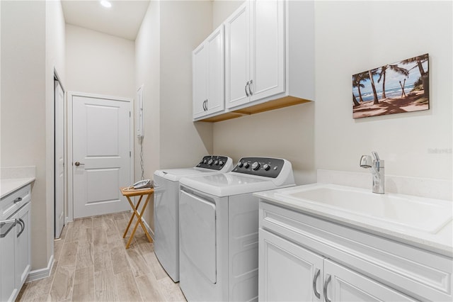 laundry area featuring independent washer and dryer, cabinets, sink, and light wood-type flooring