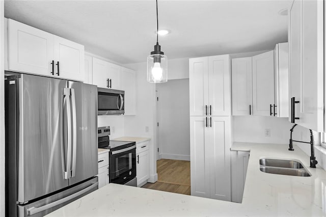 kitchen featuring decorative light fixtures, white cabinetry, and stainless steel appliances