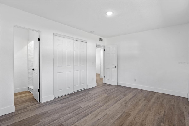 unfurnished bedroom featuring wood-type flooring and a closet