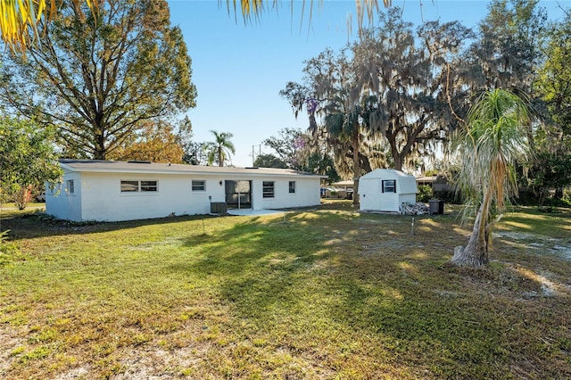 rear view of property featuring central air condition unit, a shed, and a lawn