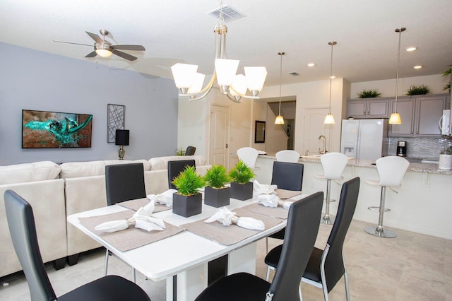 dining area featuring ceiling fan with notable chandelier and sink