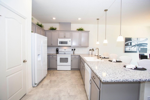 kitchen with pendant lighting, white appliances, sink, gray cabinets, and kitchen peninsula