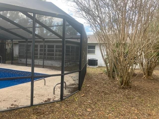 view of property exterior with glass enclosure, central air condition unit, and a patio area