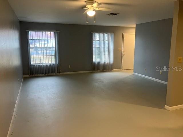 unfurnished room with ceiling fan and concrete flooring