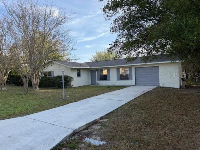 single story home featuring driveway, a front yard, and a garage