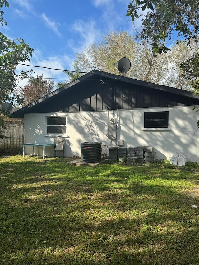 rear view of property featuring a lawn and cooling unit