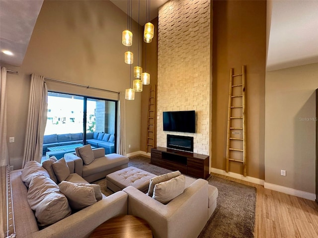 living room with a fireplace, hardwood / wood-style floors, and a towering ceiling