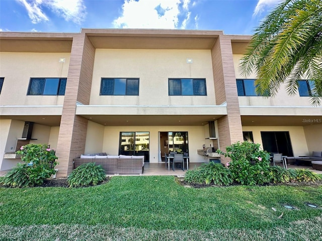 back of property featuring outdoor lounge area, a patio, and a lawn