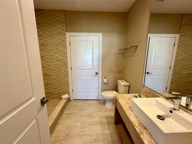 bathroom featuring tile patterned flooring, vanity, toilet, and walk in shower