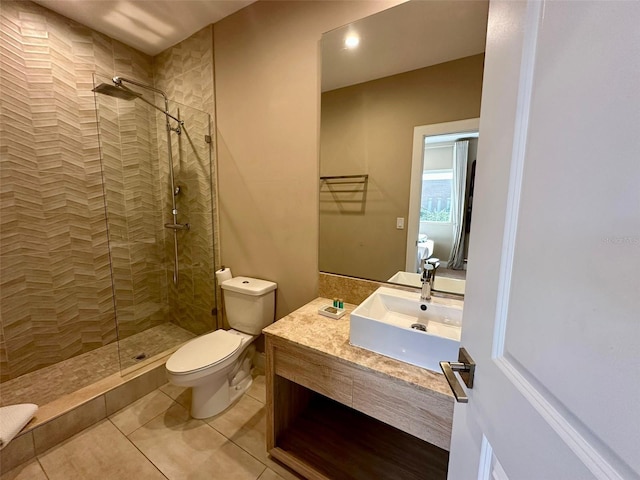 bathroom featuring tile patterned floors, vanity, toilet, and a tile shower