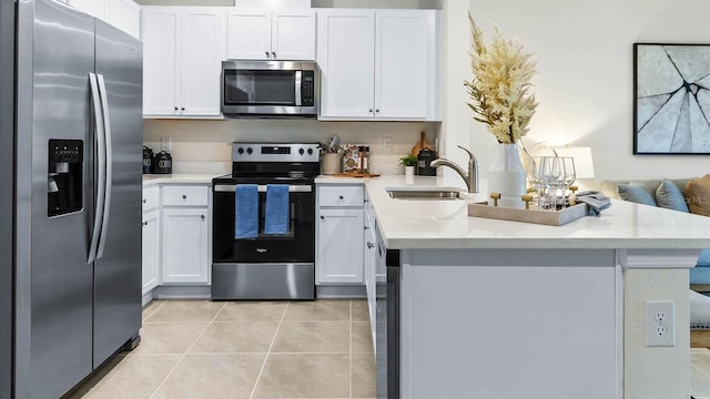 kitchen with sink, light tile patterned floors, kitchen peninsula, white cabinets, and appliances with stainless steel finishes