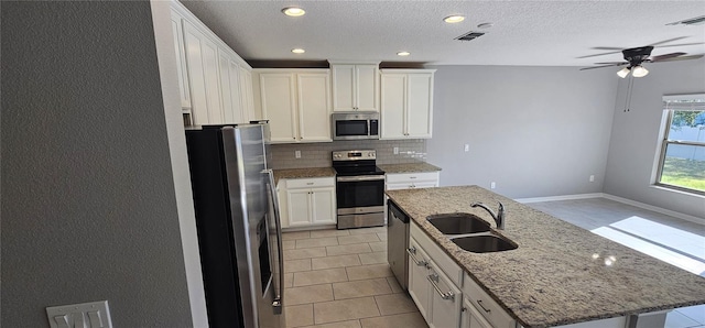 kitchen with tasteful backsplash, stainless steel appliances, sink, a center island with sink, and white cabinetry