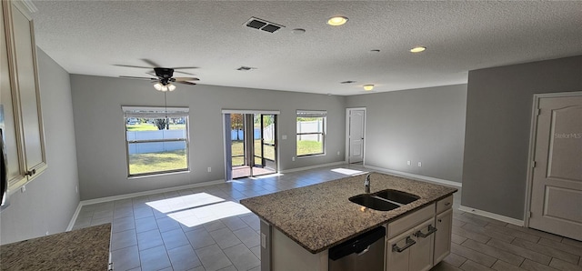 kitchen with a kitchen island with sink, sink, stainless steel dishwasher, ceiling fan, and a textured ceiling