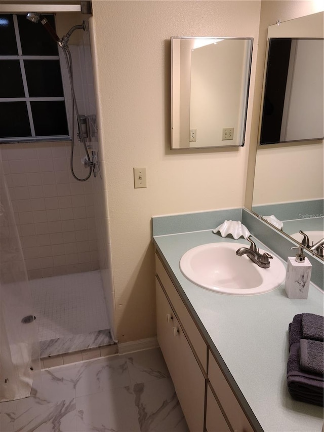 bathroom featuring tiled shower and vanity