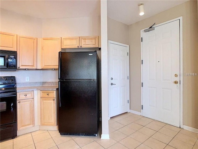 kitchen with light brown cabinetry, light tile patterned flooring, and black appliances