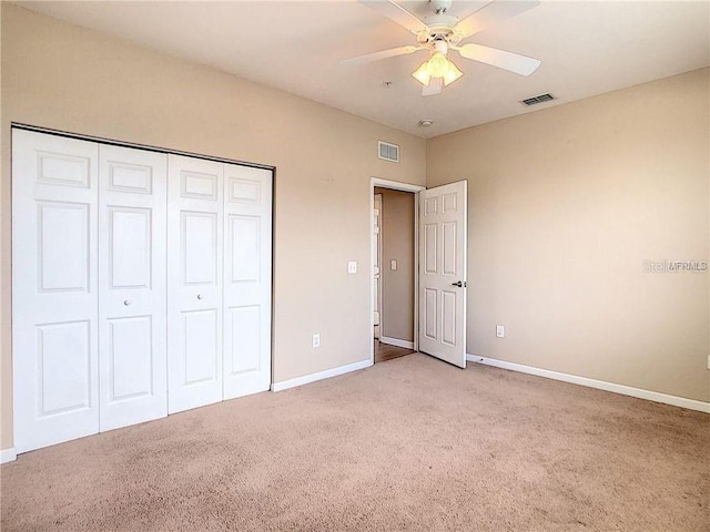 unfurnished bedroom with ceiling fan, light colored carpet, and a closet