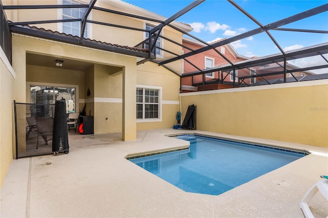 view of swimming pool with glass enclosure and a patio