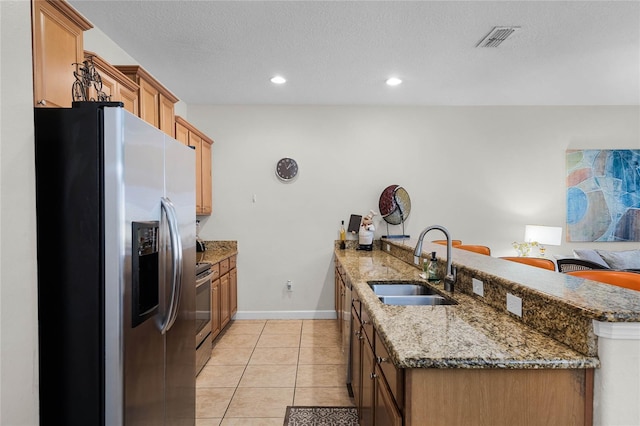 kitchen featuring kitchen peninsula, stainless steel appliances, light tile patterned flooring, and sink