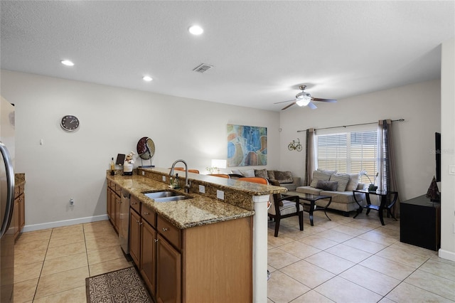 kitchen with kitchen peninsula, light stone counters, ceiling fan, sink, and light tile patterned flooring