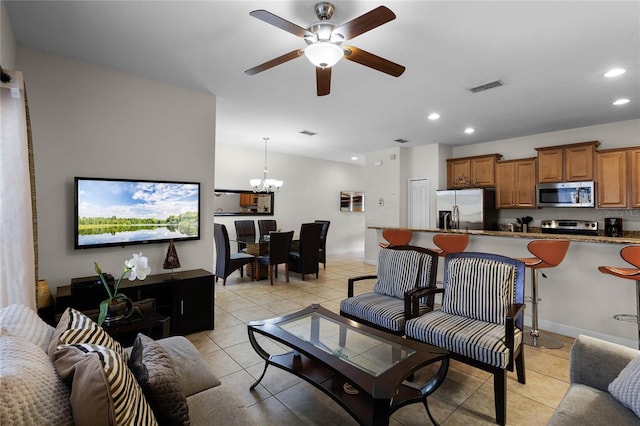 tiled living room with ceiling fan with notable chandelier