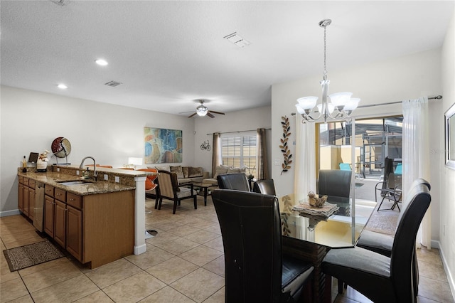 tiled dining room with sink, ceiling fan with notable chandelier, and a textured ceiling