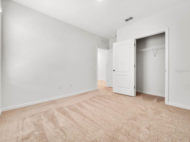 unfurnished bedroom featuring light carpet and a closet