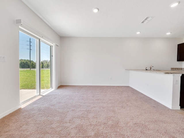 unfurnished living room featuring light carpet and sink