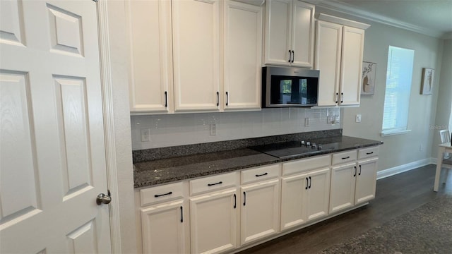 kitchen featuring white cabinetry, dark wood-type flooring, dark stone counters, black electric cooktop, and ornamental molding