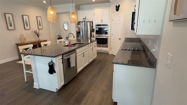 kitchen featuring a kitchen island with sink, sink, decorative light fixtures, white cabinetry, and stainless steel appliances