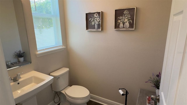 bathroom with toilet, plenty of natural light, and sink