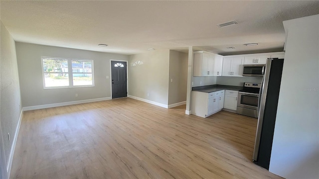 kitchen featuring stainless steel appliances, white cabinetry, a textured ceiling, and light hardwood / wood-style flooring