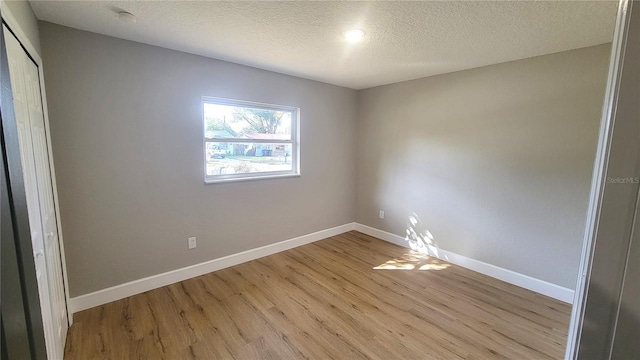 unfurnished room with light hardwood / wood-style flooring and a textured ceiling