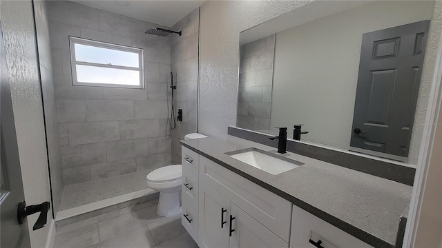 bathroom featuring tiled shower, vanity, toilet, and tile patterned floors