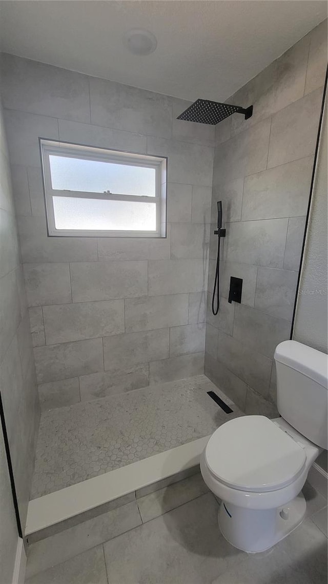 bathroom featuring a tile shower and toilet