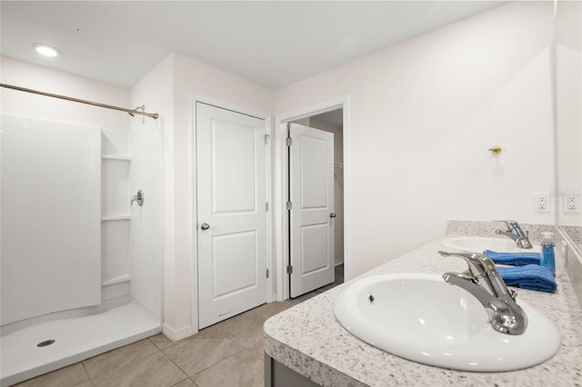 bathroom with walk in shower, vanity, and tile patterned flooring