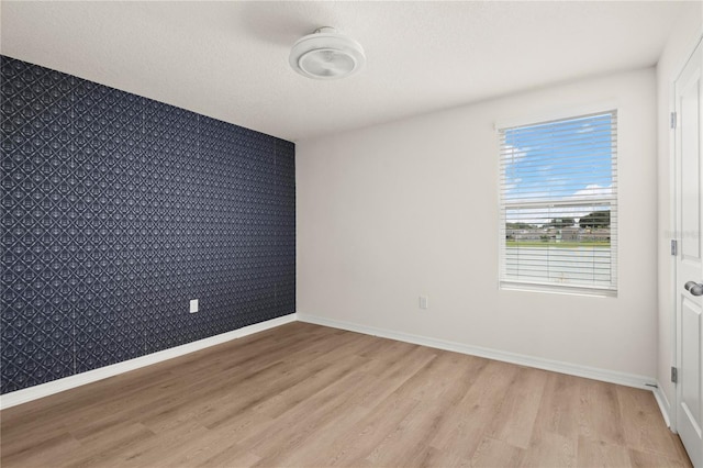 unfurnished room featuring a textured ceiling and light wood-type flooring