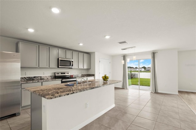 kitchen featuring appliances with stainless steel finishes, dark stone countertops, visible vents, and gray cabinetry