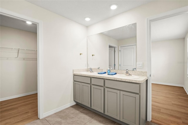 bathroom with a sink, a spacious closet, baseboards, and double vanity