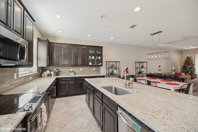 kitchen featuring sink, hanging light fixtures, light stone counters, light tile patterned flooring, and appliances with stainless steel finishes