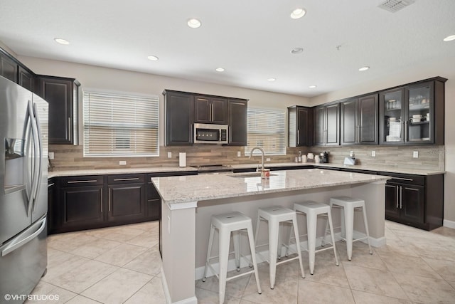 kitchen with sink, a center island, light tile patterned flooring, and appliances with stainless steel finishes