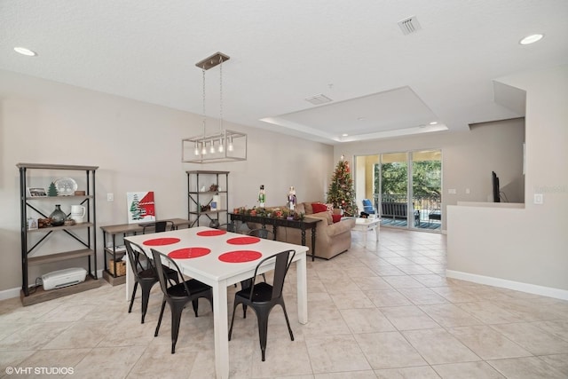 tiled dining room with a raised ceiling